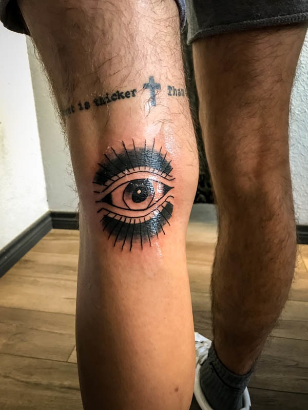 Traditional all-seeing eye tattoo on the back of a knee
