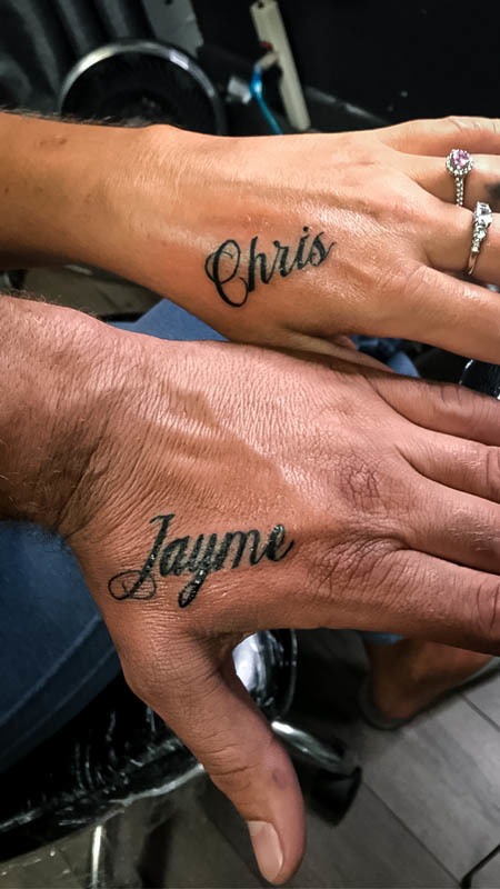 Matching script name tattoos on two hands