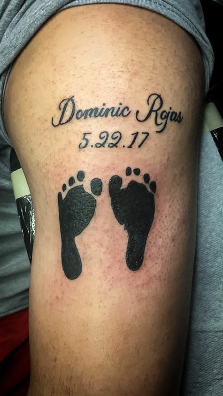 Memorial tattoo with baby footprints, a name and a date