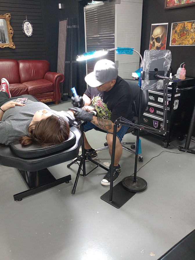 Tattoo artist working on a client's arm
