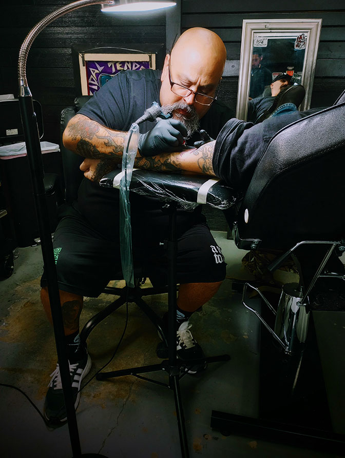 Tattoo artist tattooing a client's forearm