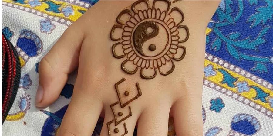 Henna design with a yin-yang flower on the back of a hand